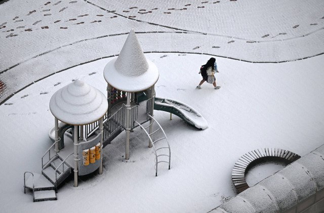 Seorang siswa berjalan melintasi taman bermain yang tertutup salju di Goyang, Korea Selatan, Rabu (27/11/2024). Foto: JUNG YEON-JE / AFP