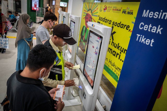 Petugas membantu penumpang mencetak tiket kereta api di Stasiun Gambir, Jakarta, Kamis (29/2/2024). Foto: Bayu Pratama S/ANTARA FOTO