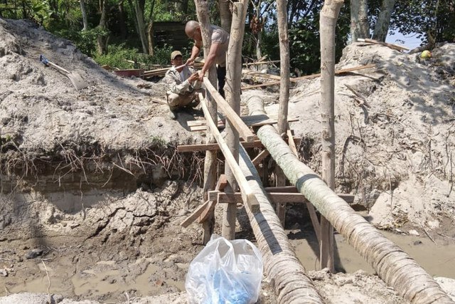 Polisi membangun jembatan di rumah warga di Kabupaten Samosir, Sumut, yang terisolasi lantaran sekelilingnya digali imbas masalah warisan. Foto: Istimewa